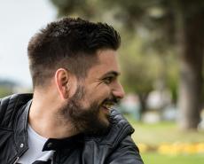 Uomo sorridente all'aperto, atmosfera serena e gioiosa.