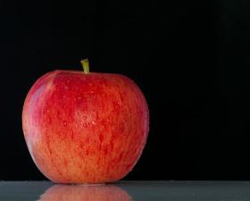 Mela rossa su sfondo nero, fresca e succosa.
