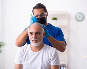 Medico esamina il cuoio capelluto di un paziente in clinica.