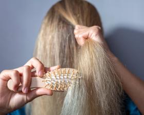 Persona che si pettina i capelli biondi con una spazzola.