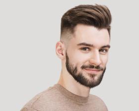 Uomo con barba e capelli pettinati all'indietro, sorriso accennato.