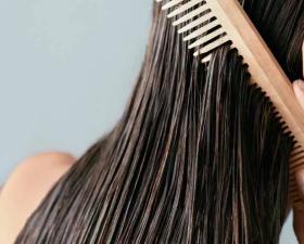 Donna pettina capelli bagnati con pettine di legno.